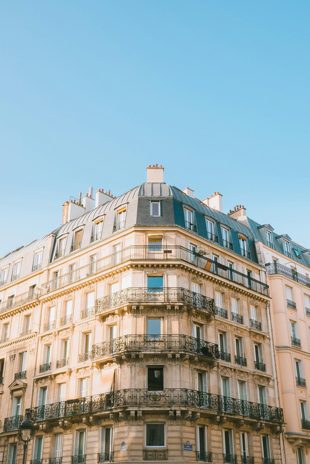 Immeuble haussmannien parisien en pierre de taille, façade d'angle avec balcons en fer forgé